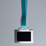 A rectangular medal with a black velcro back, attached to a bright turquoise ribbon lanyard, shown against a plain light gray background to attach your hyrox patch
