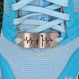 A stainless steel shoe tag with a netball motif placed on a blue shoe lace, the tag has a laser-cut design that resembles a heartbeat line.