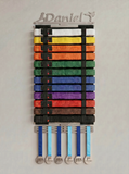 Belt display with colorful martial arts belts and medals with the option to personalise the hanger on a gray background. The name Daniel is on this one
