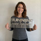 Woman holding a stainless seel medal hanger with 'RUNNING Cheaper than therapy 