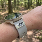 Smartwatch with a band that says 'I Don't Quit' on a wrist in a forest setting SA Medal Hangers Watch Tag