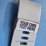Personalized metal name tag on a white strap with text 'YOUR OWN TEXT HERE' against a blue background.