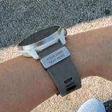 Smartwatch with customizable watch tag on a wrist, set against a natural background.