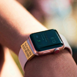 Black smartwatch with a motivational band on a pink background with the taxt youve got this keep moving the watch tag