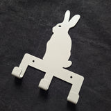 grey metal wall hook shaped like a rabbit on a dark gray background